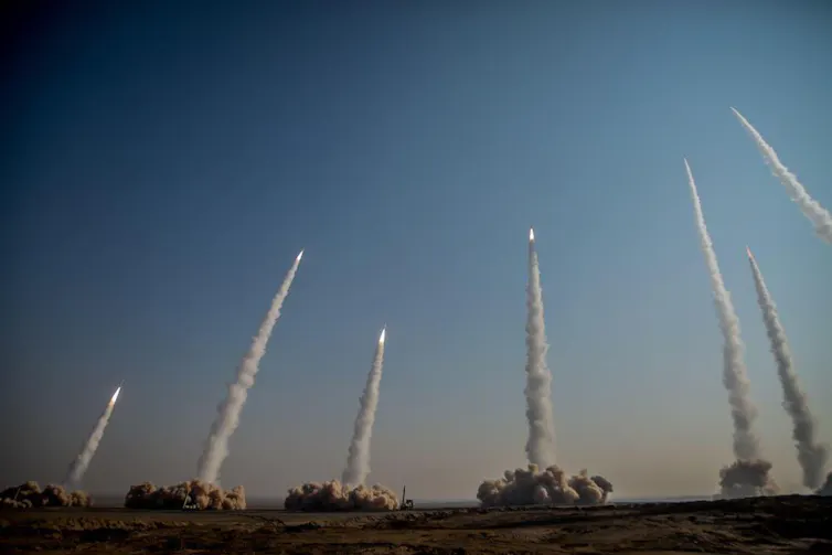 seven bright dots against a clear sky, each trailing a plume of smoke to the ground