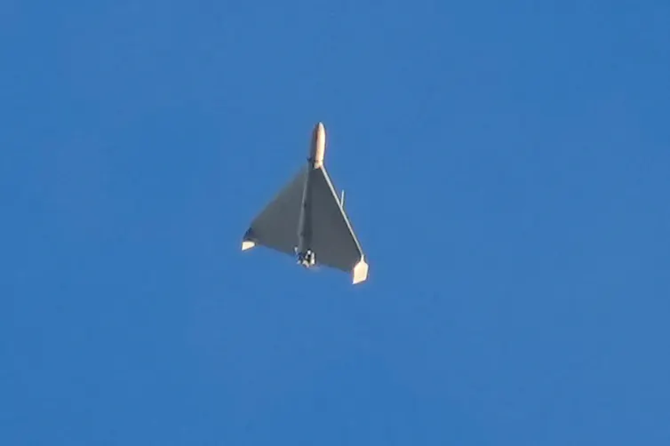 a small delta-wing aircraft flies against a clear blue sky