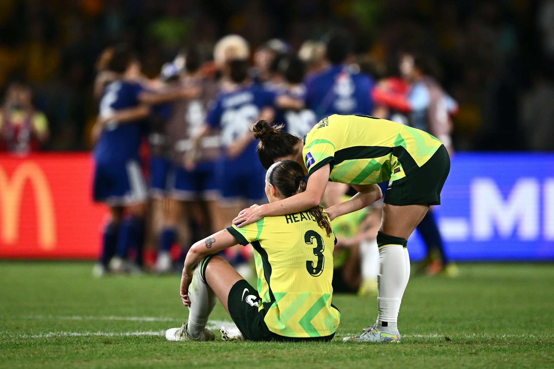 Several Matildas console each other as the Japanese team celebrate.
