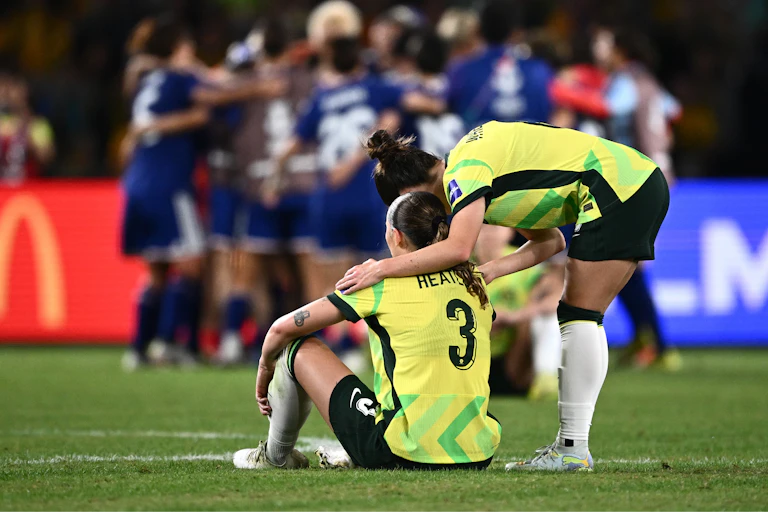 Several Matildas console each other as the Japanese team celebrate.
