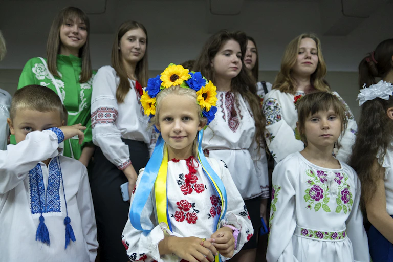 Schoolchildren pose for a photo, one with sunflowers in her hair.