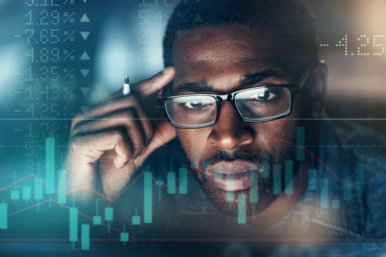 A man stares at numbers and graphs on a screen