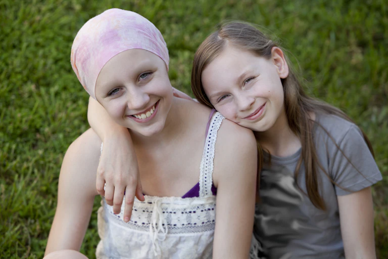 Two young children, with one wearing a head scarf, suggesting cancer treatment