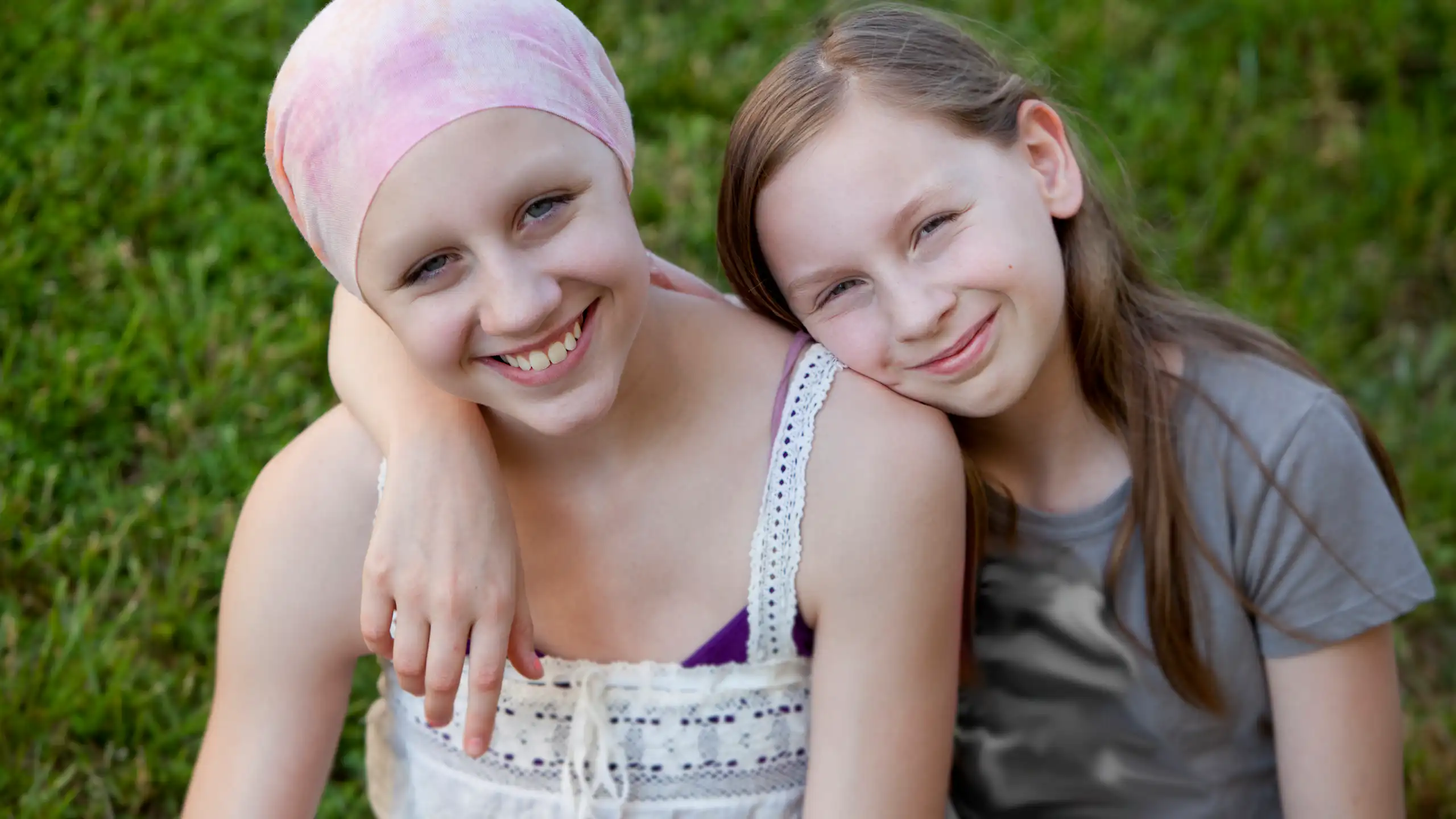 Two young children, with one wearing a head scarf, suggesting cancer treatment