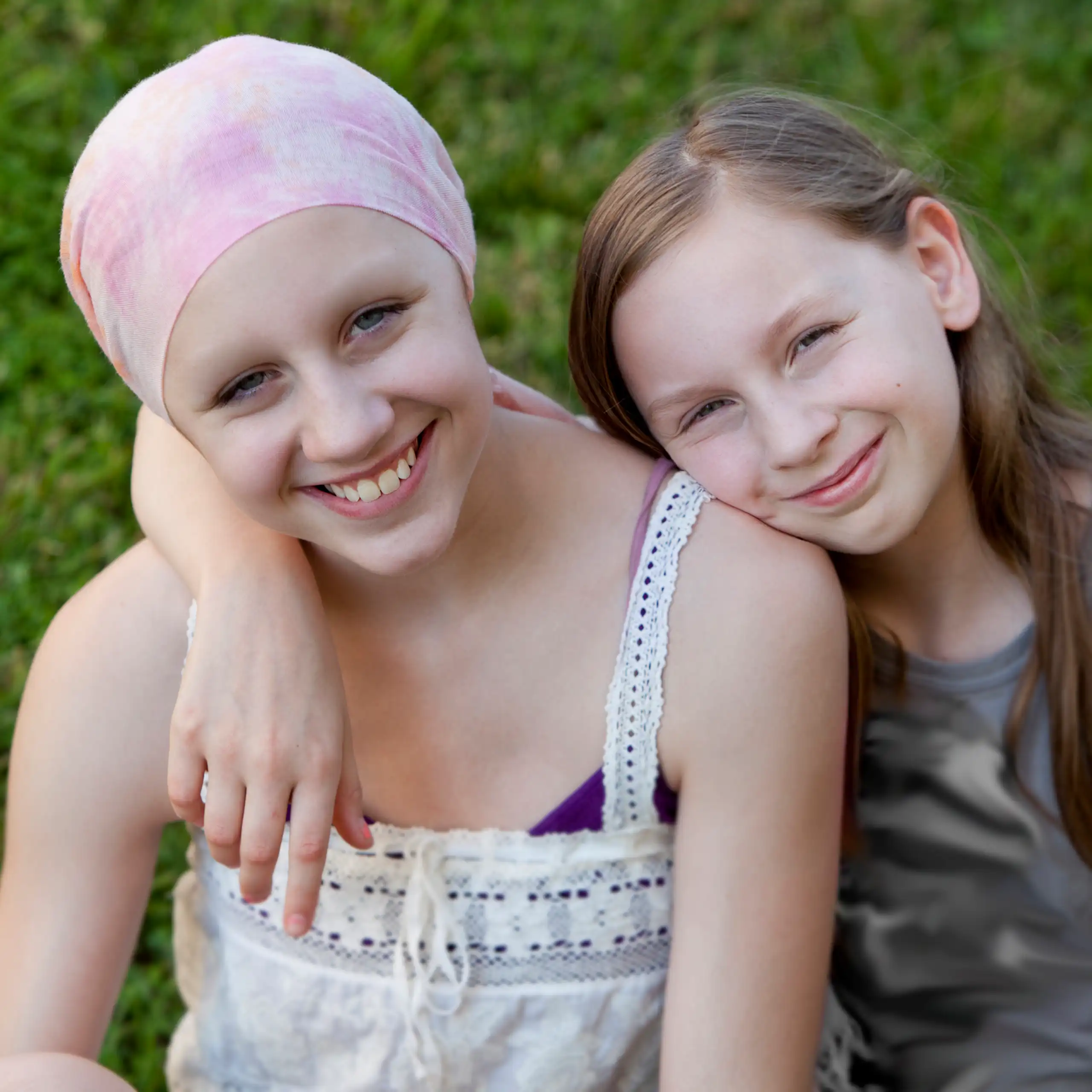 Two young children, with one wearing a head scarf, suggesting cancer treatment