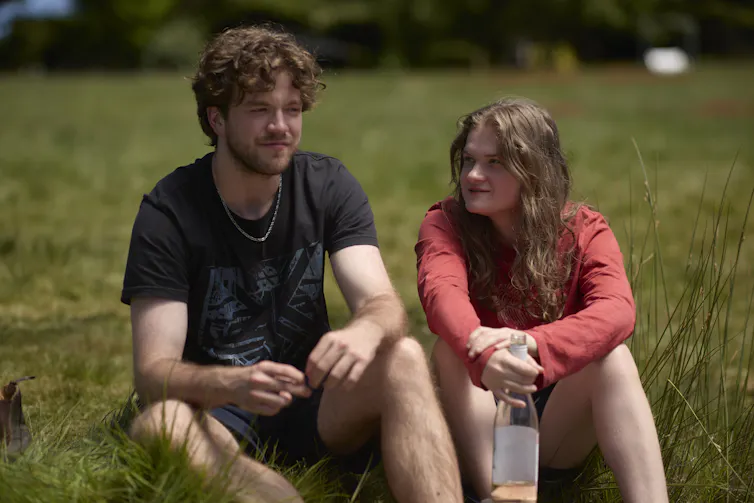 Production image: Dee and Darcy sit in a grassy field.