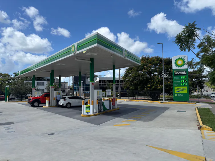 Two cars at a largely empty petrol station