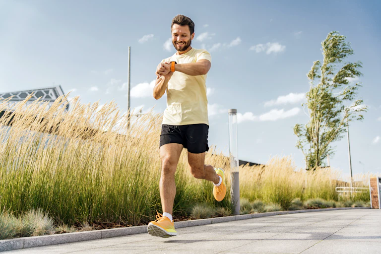 A man checks his fitness watch while running.