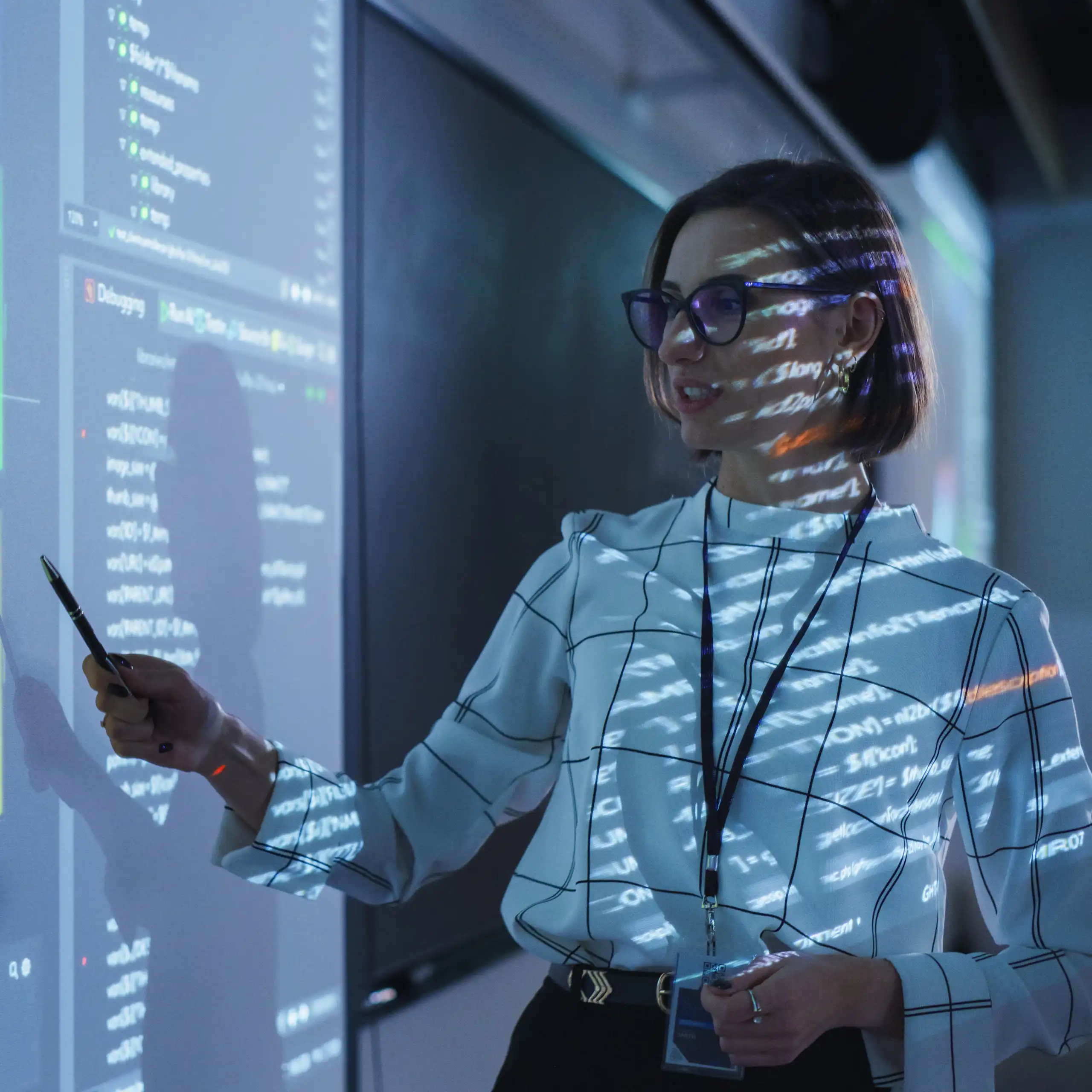Jeune enseignante donnant une présentation de données scientifiques dans un auditorium sombre avec projection d'un diaporama.