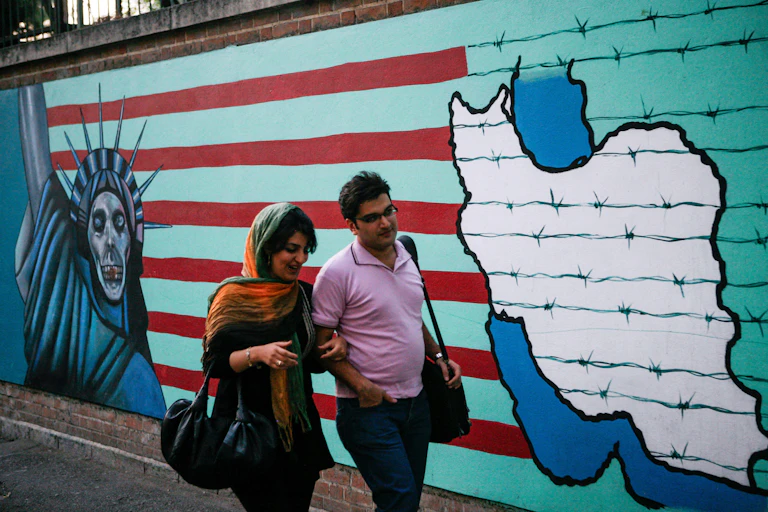 A man and woman walk past an anti-US mural on the walls of the former US embassy in Tehran.
