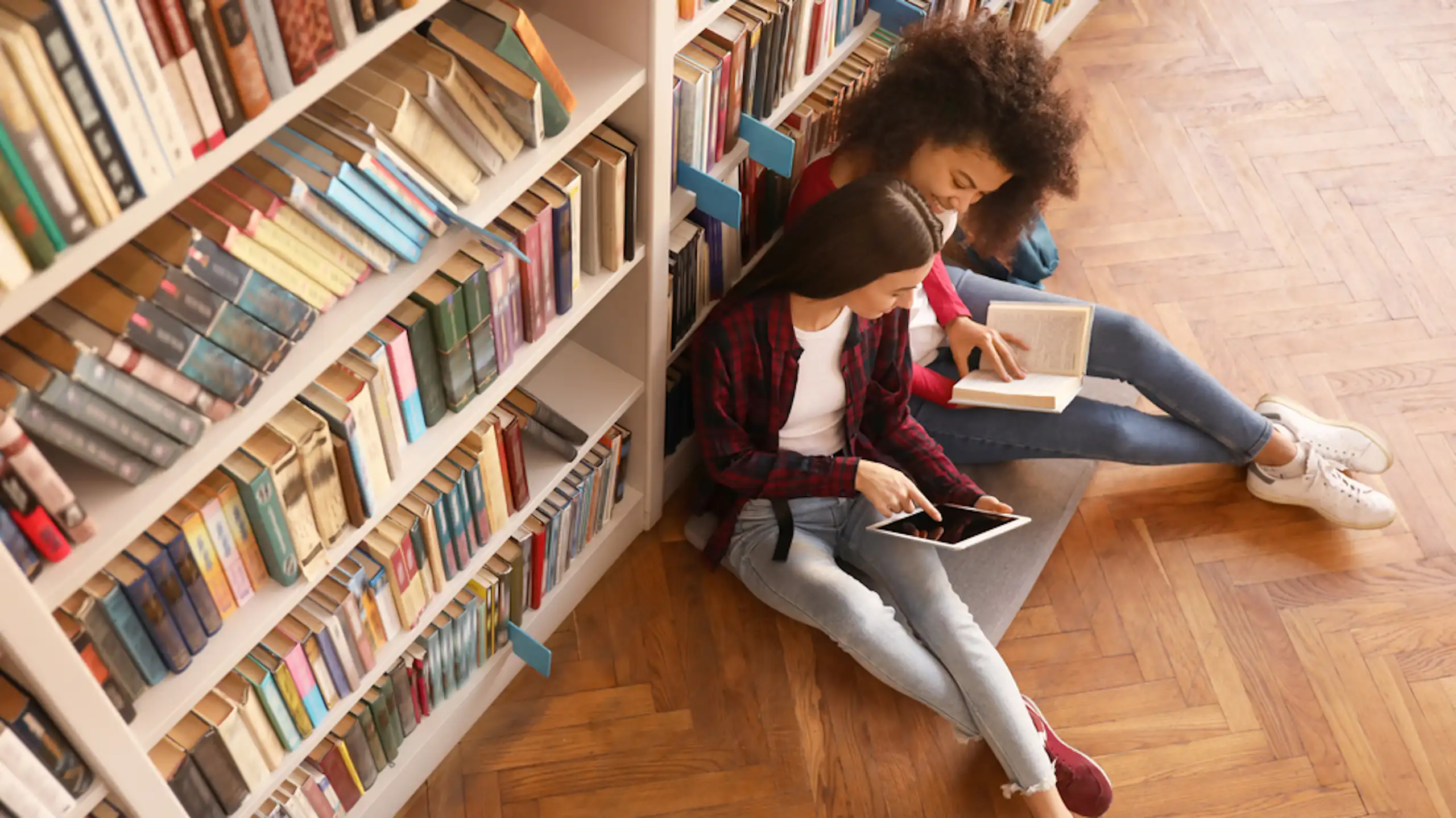 Deux étudiantes en train de lire dans une bibliothèque.