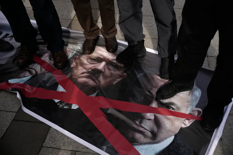 People from the knees down standing on photographs of two men's heads/