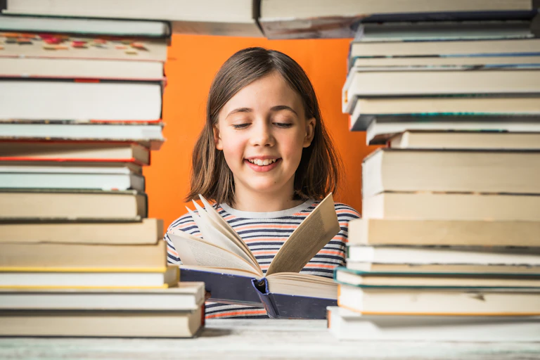 Una niña lee enmarcada por dos columnas de libros
