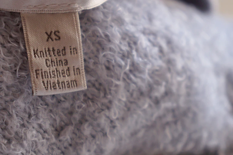 clothing label on a grey jumper that reads 'knitted in china, finished in vietnam'