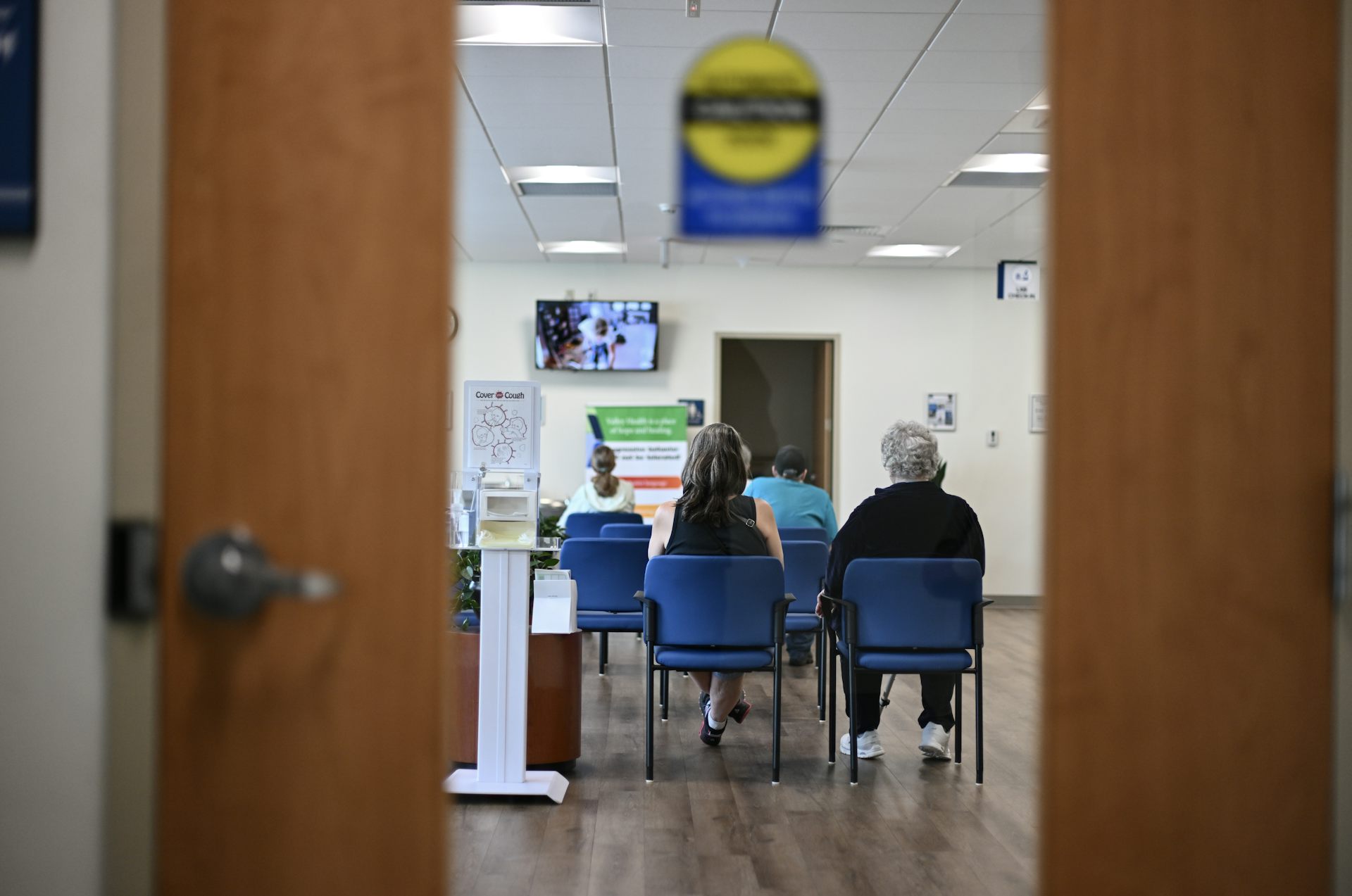 View of people sitting in blue chairs in hospital waiting room