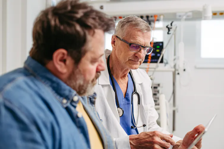 Patient sitting with white-coated doctor looking at tablet