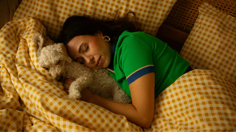Une femme dormant dans un lit avec un chien