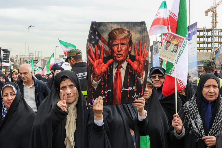a demonstration in Iran, women hold a sign of Donald Trump with bloody hands