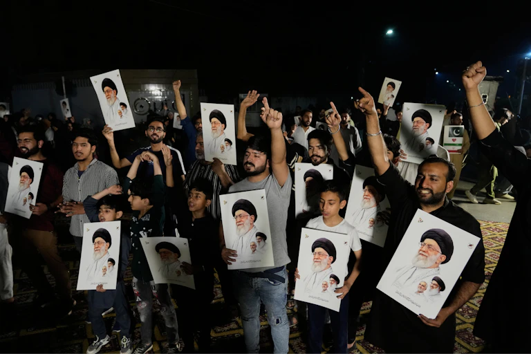 Several men, holding photos of Ayatollah Khamenei, raise their arms in protest.