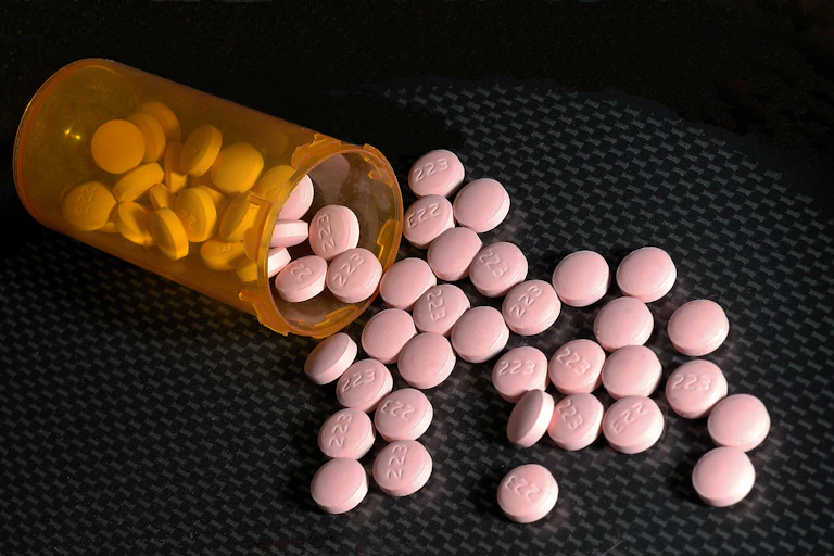 Pink lithium pills spilling out of an orange bottle.