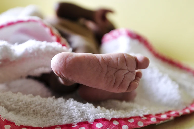 Baby sleeping on a blanket; only the foot is visible