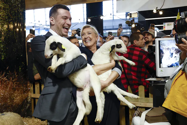 RN leader Marine le Pen and party president Jordan Bardella hold baby lambs and share a joke while campaigning in Paris, February 2026.
