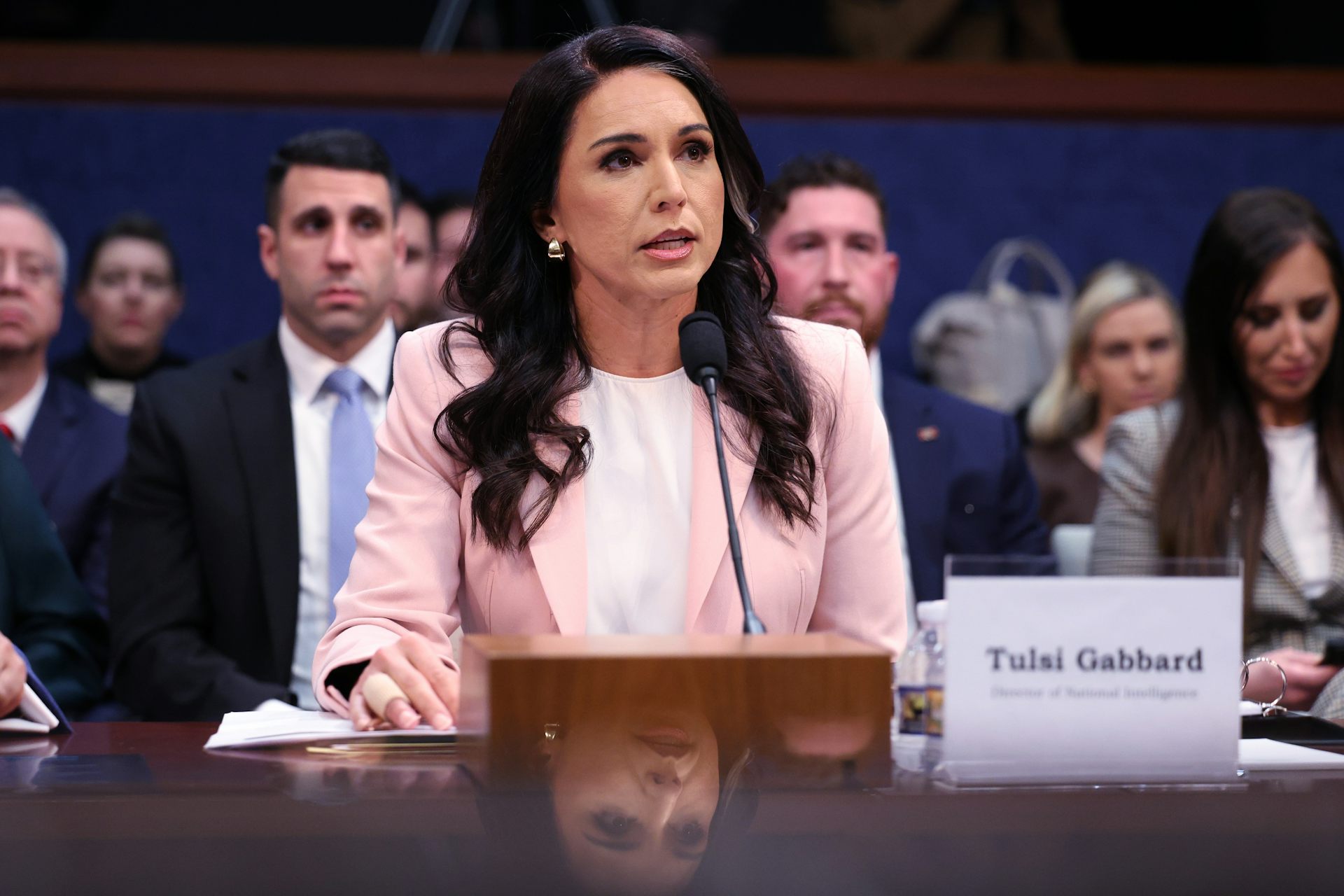 A woman with long dark hair in a pink jacket.