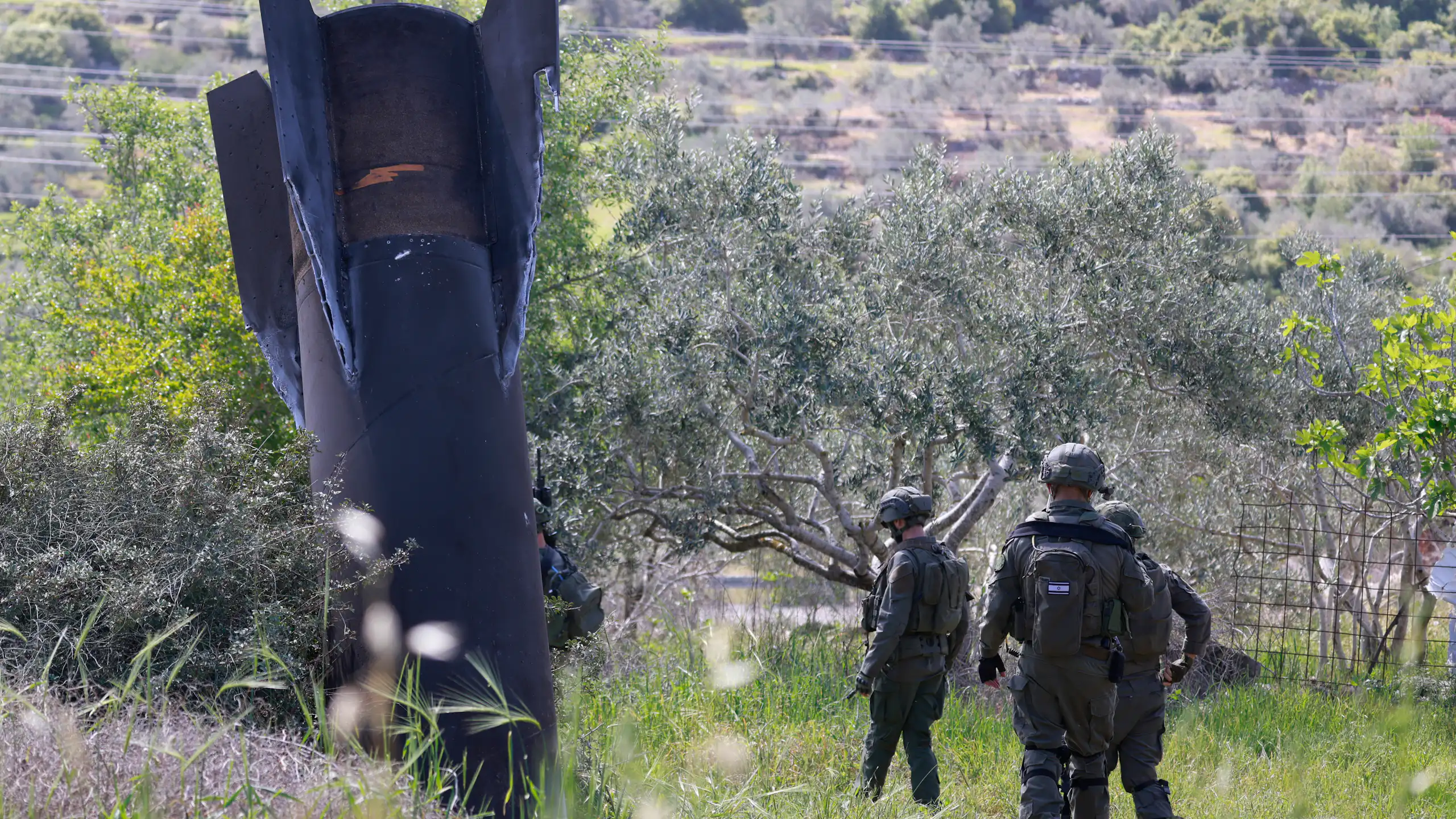 Des soldats israéliens au pied d'un missile iranien planté dans un champ d'oliviers.