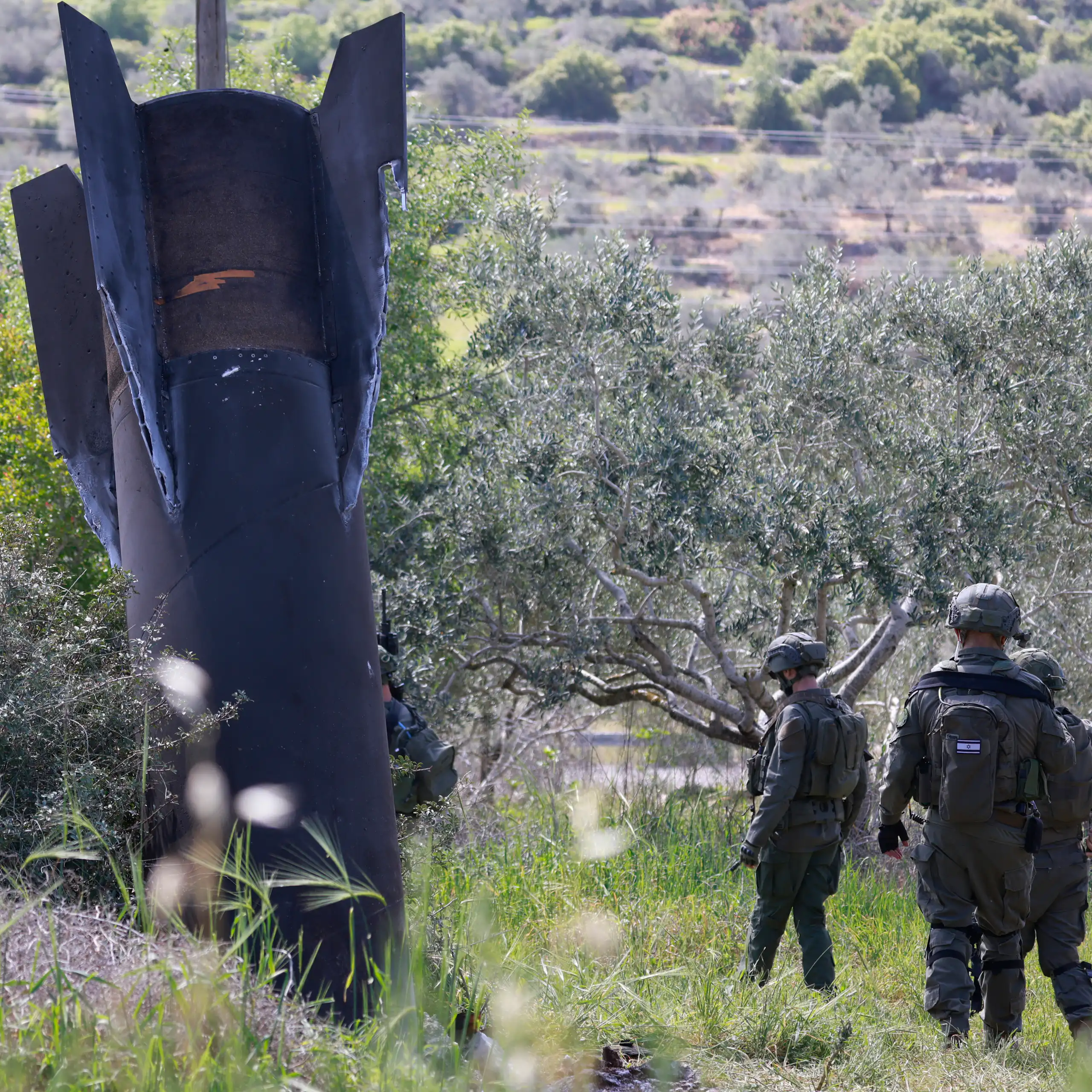 Des soldats israéliens au pied d'un missile iranien planté dans un champ d'oliviers.
