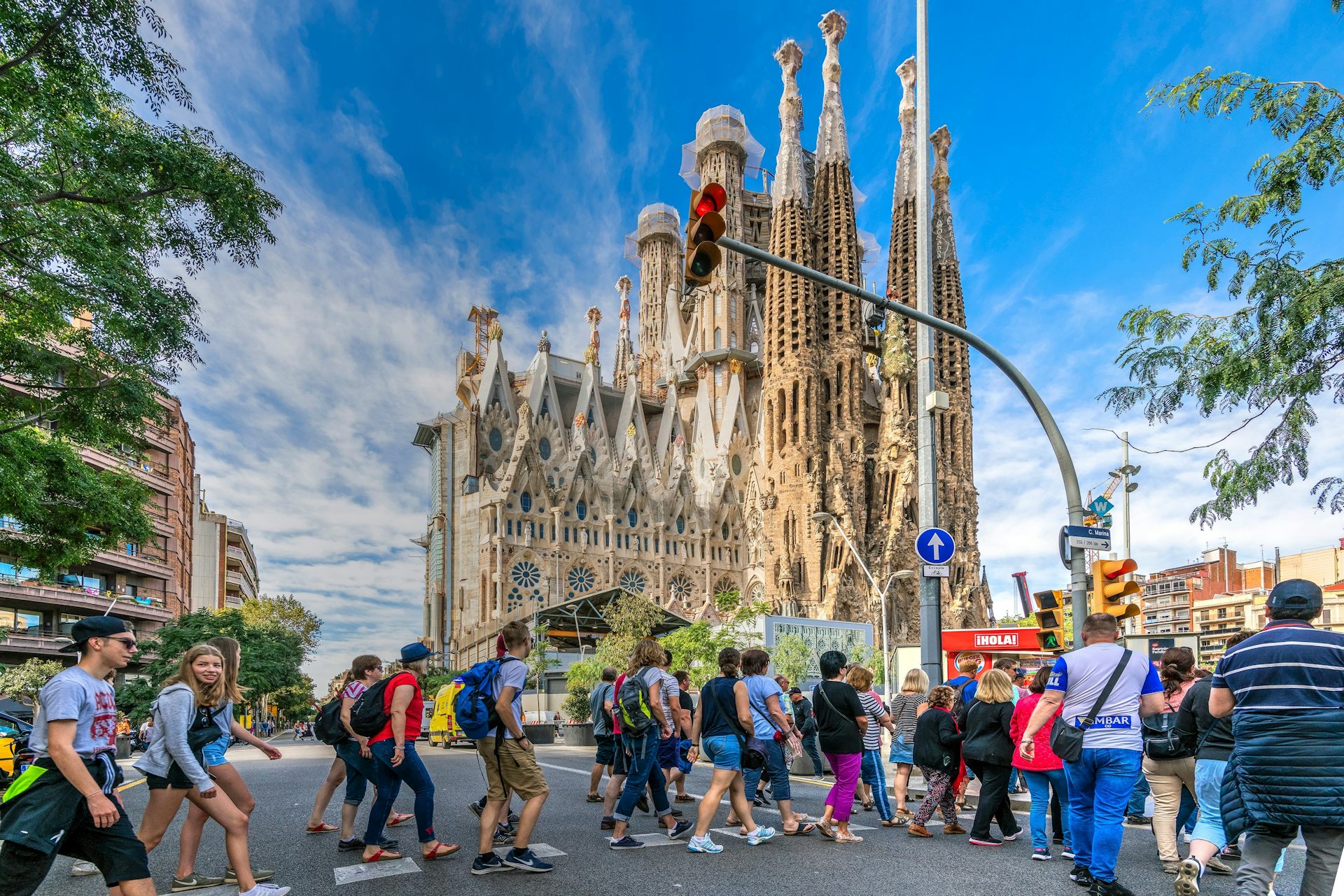 Molta gent creua un pas de vianants davant la Sagrada Família de Barcelona.