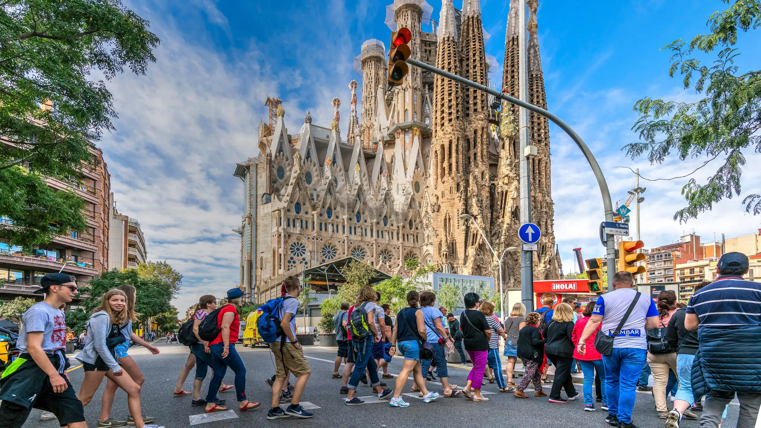 Molta gent creua un pas de vianants davant la Sagrada Família de Barcelona.