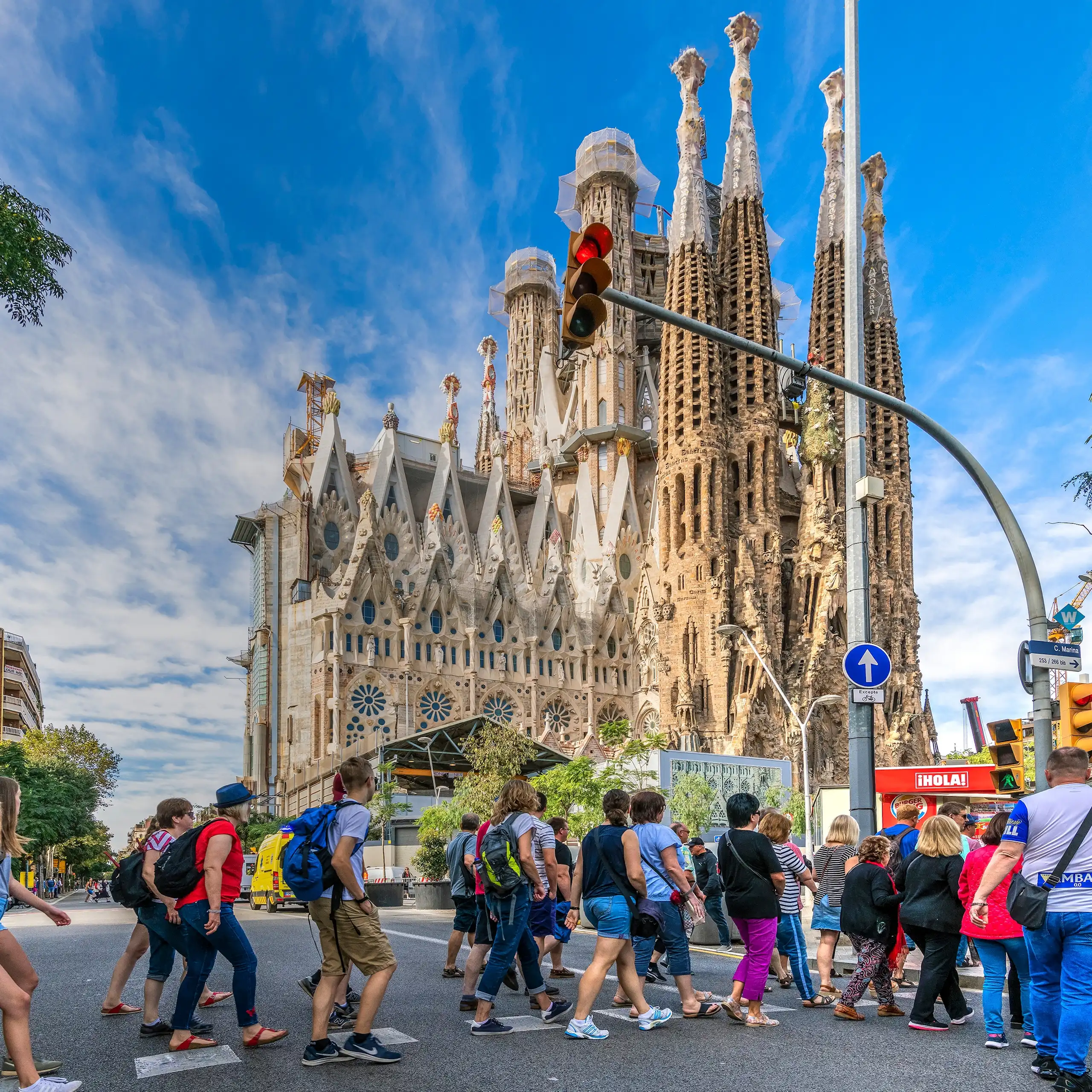 Molta gent creua un pas de vianants davant la Sagrada Família de Barcelona.