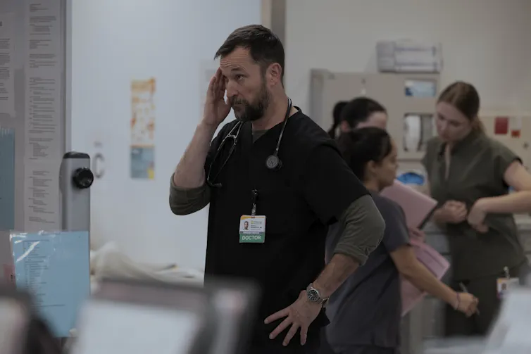 A US doctor in scrubs looking overwhelmed