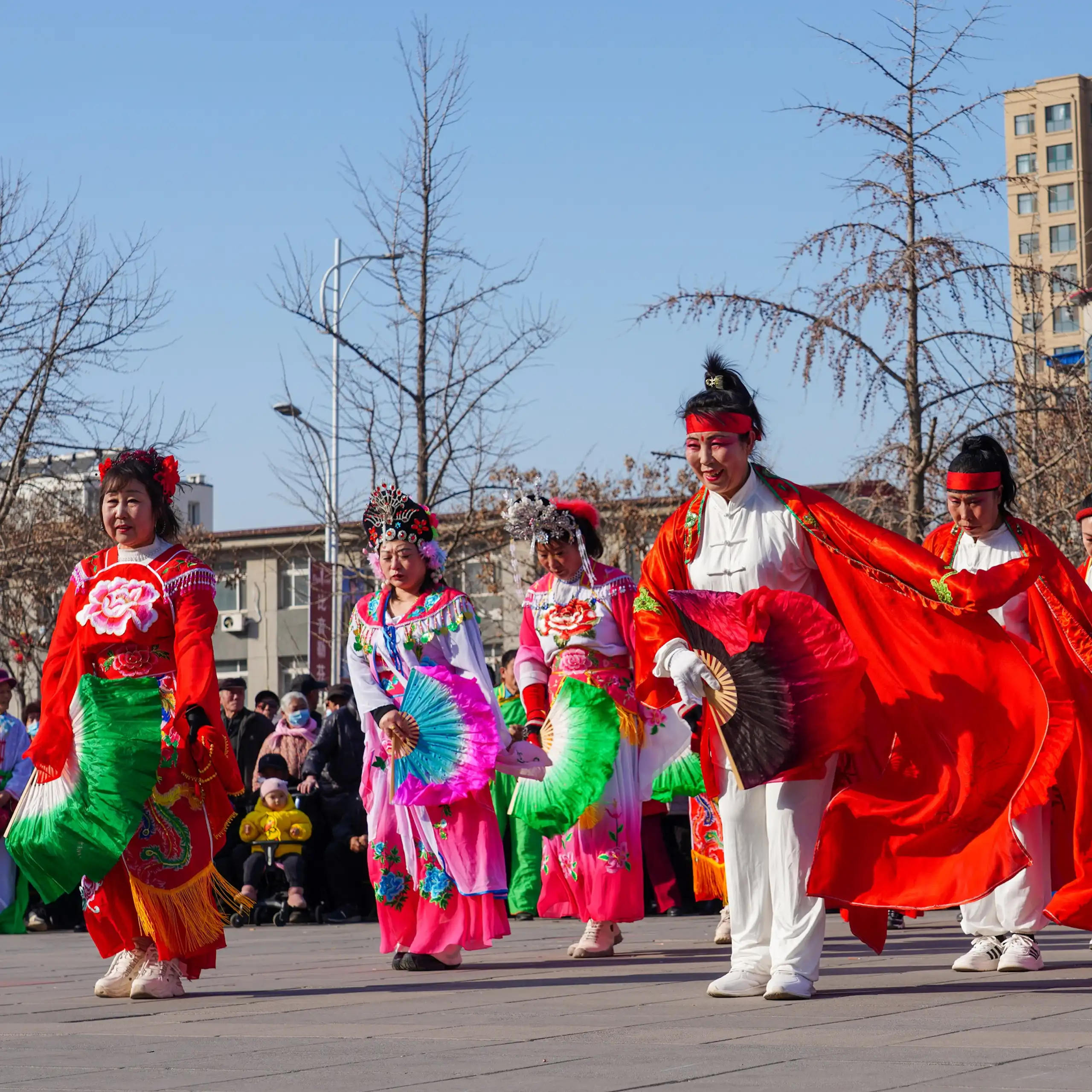 Personas con trajes coloridos bailan en la calle.