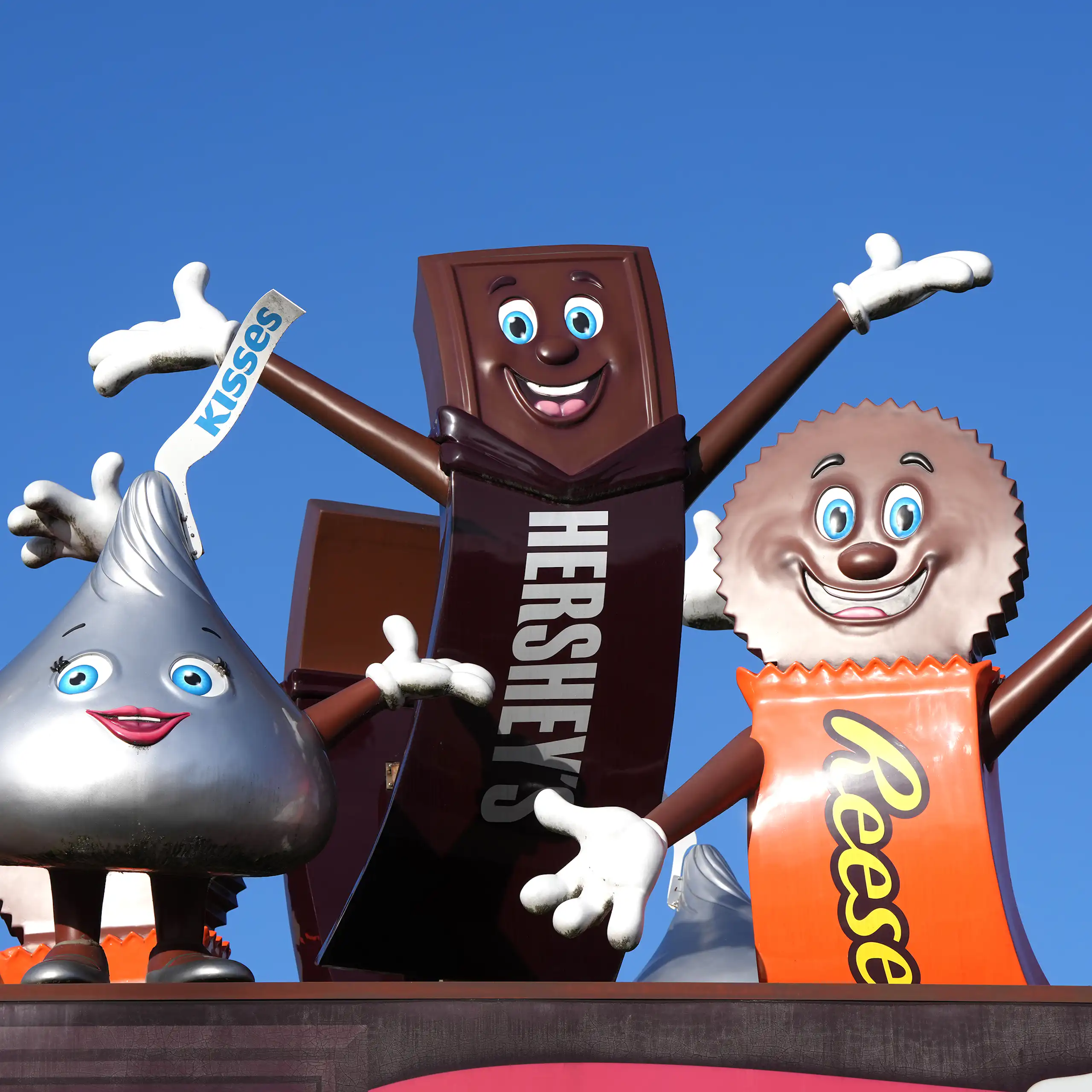 Statues of a smiling and waving Hershey's Kiss, Hershey's Chocolate Bar and Reese's Peanut Butter Cup