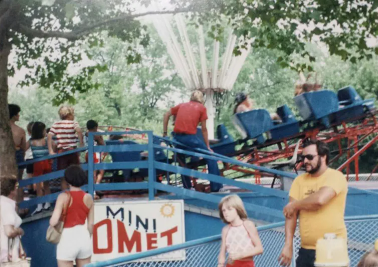 Adults and children on and around an amusement ride called 'Mini Comet'