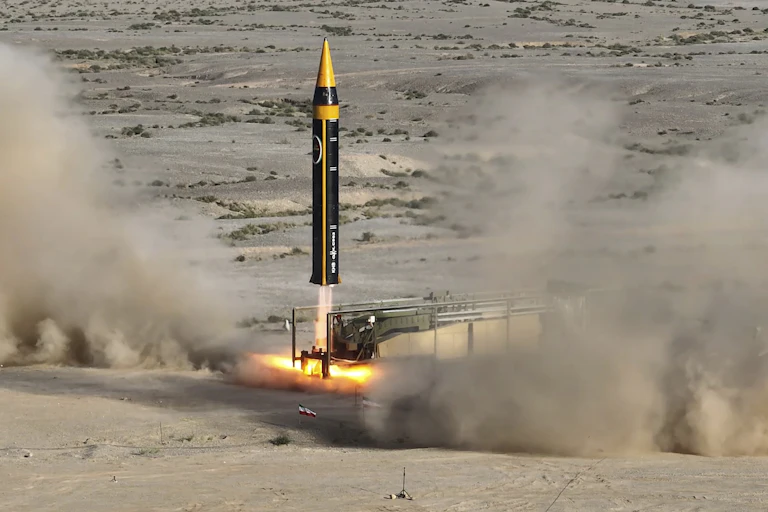 a large missile just beginning to lift off from a desert landscape
