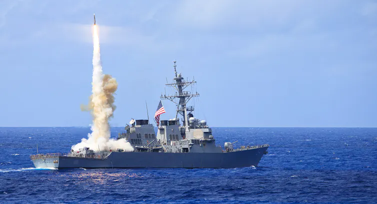 a missile rises from a navy warship at sea
