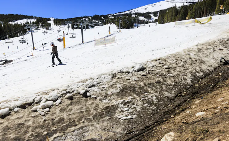 A skier next to open ground with a mountain in the background.
