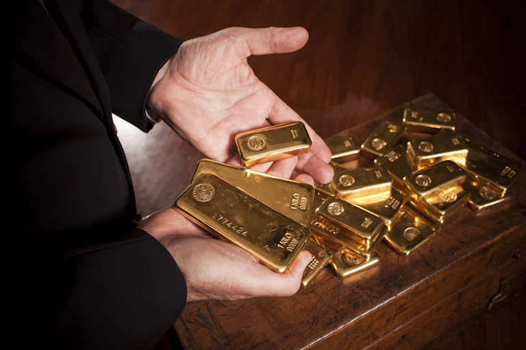Person's hands holding gold bars