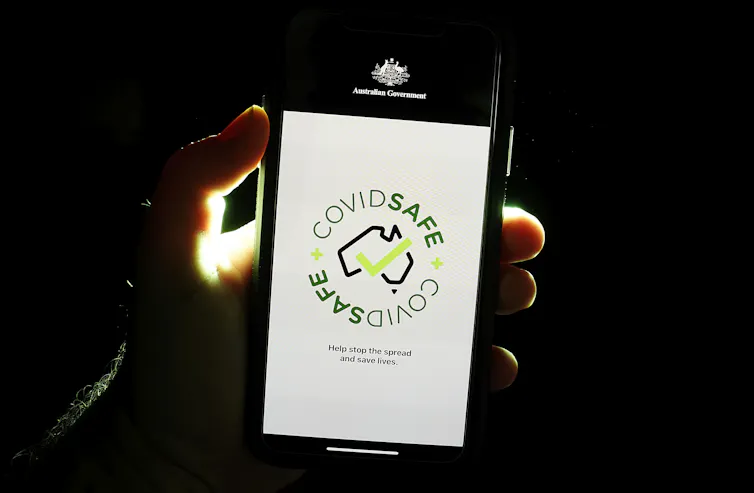 A hand holding a smartphone screen that says COVIDSafe and the Australian government logo