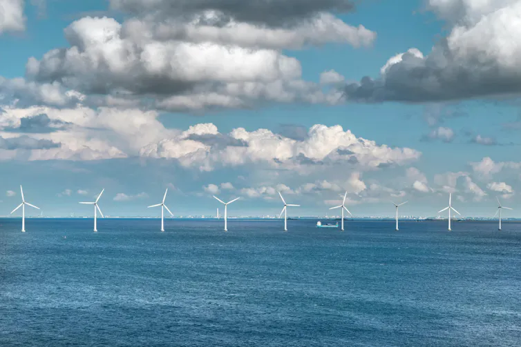 A line of wind turbines in the sea.