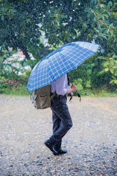 Business professional walking in rain with umbrella