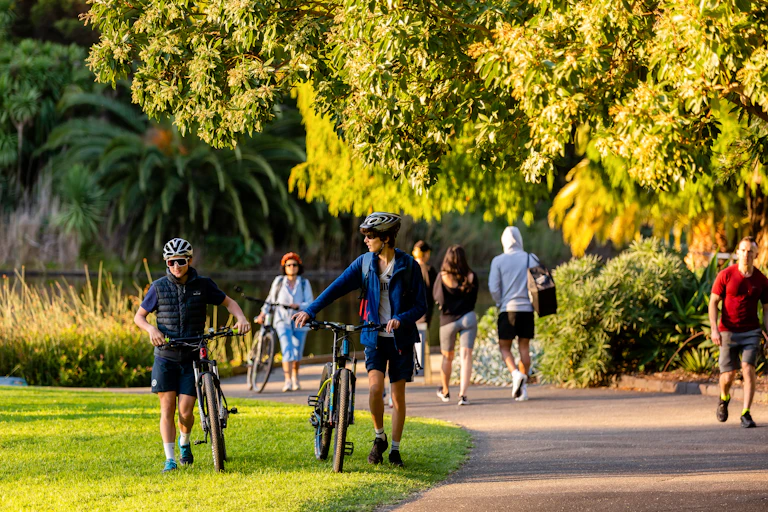 Two cyclists walk on the paths of the Botanical Gardens in Melbourne.