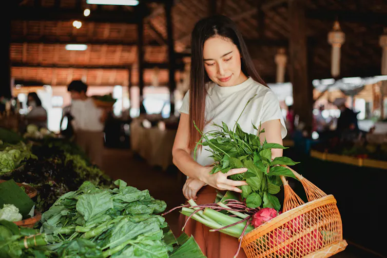 A woman buys fresh greens at a farmer's market.