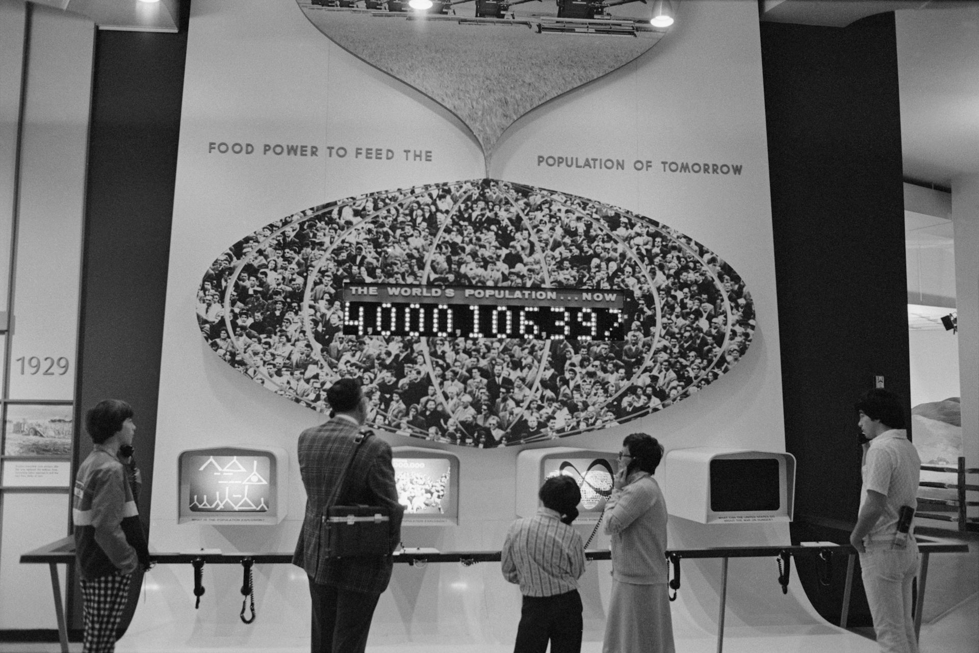 People listen at an exhibit displaying a population of just over 4 billion.