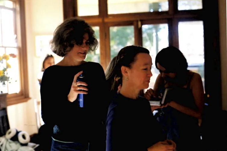 a woman styling her friend's hair