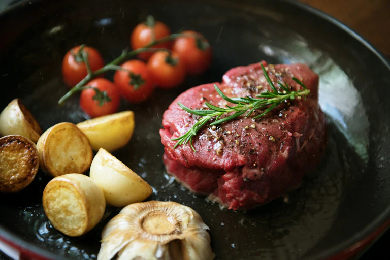 A raw steak with potatoes and fresh vine tomatoes.