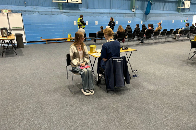 Students receiving vaccines and antibiotics from medical staff in the sports hall at the University of Kent campus in Canterbury.
