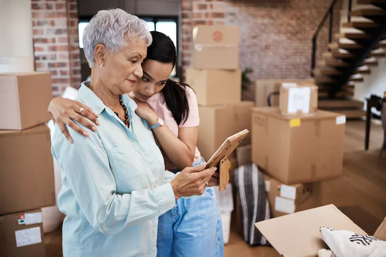 Two people looking at an ipad surrounded by boxes.